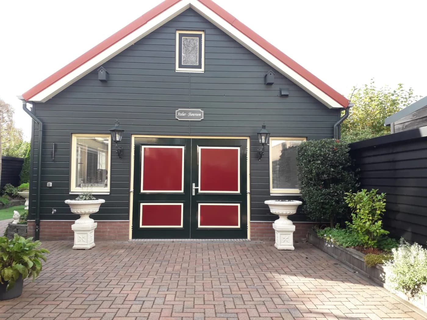 Jans werkplaats met houten gevel en rode deurpanelen
